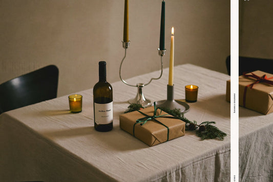 Gedekte tafel met kaarsen, een fles wijn en ingepakte cadeaus