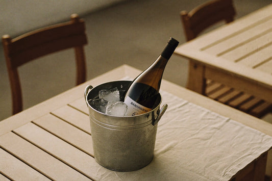 Fles wijn in een ijsemmer op een houten tuintafel