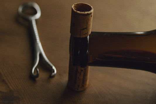 Kurk en kurkentrekker naast een geopende fles wijn op een houten tafel